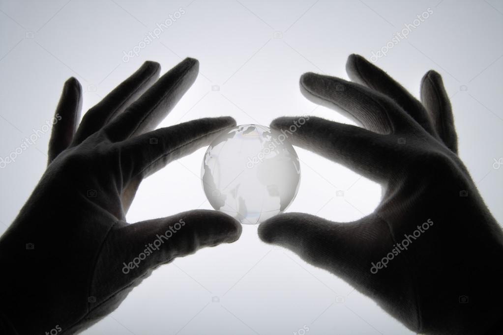 Human hand with cotton gloves holding glass globe against white 