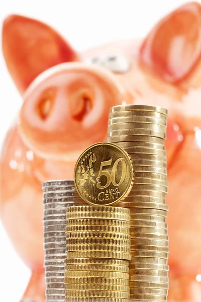 Piggy bank met stapels van euro-muntstukken op witte achtergrond — Stockfoto