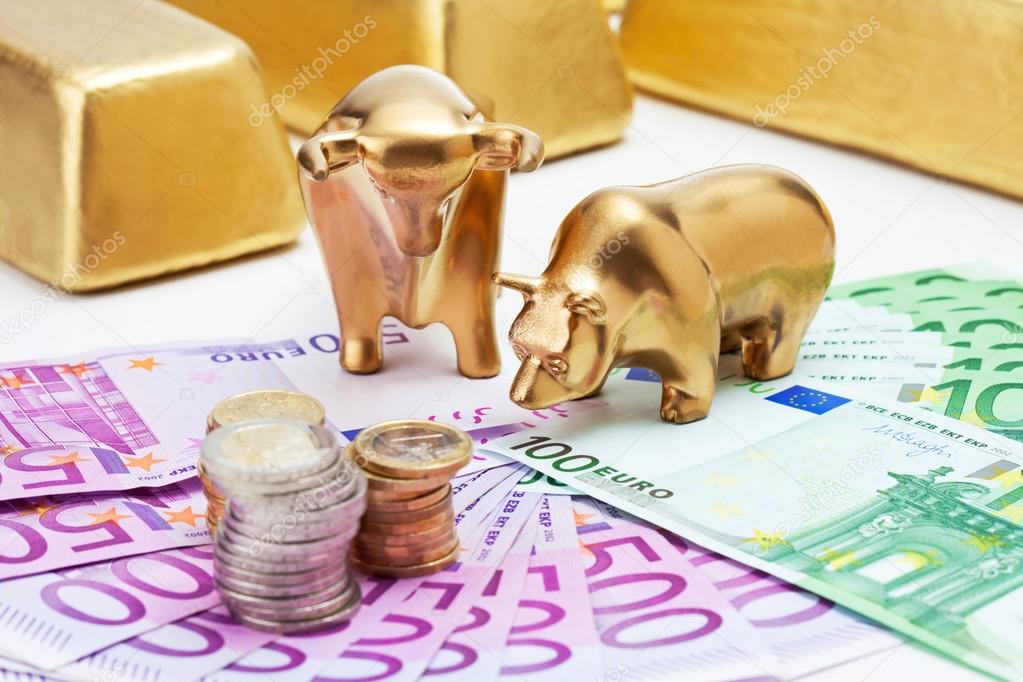 Golden bear, bull figurines with euro coins  gold bars on fanned