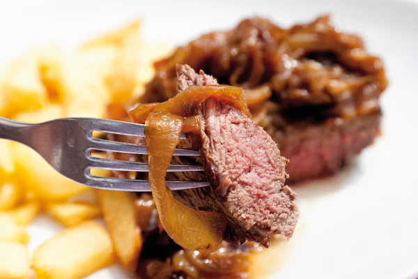 Close up de bife com cebola frita e batatas fritas — Fotografia de Stock