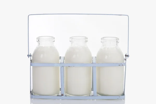 Primo piano di bottiglie di latte in rack su sfondo bianco — Foto Stock
