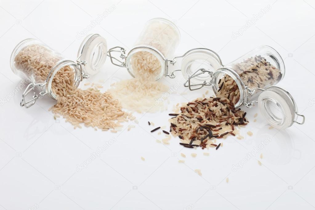 Mixed rice grains in glass jars on white background