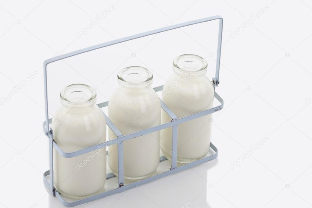 Close up of milk bottles in rack on white background