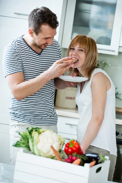 Par i køkken, spise brød med tomat - Stock-foto