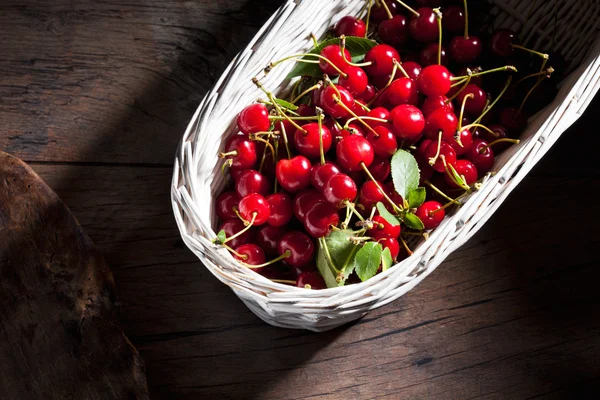 Sour cherries in basket on wood — Stock Photo, Image