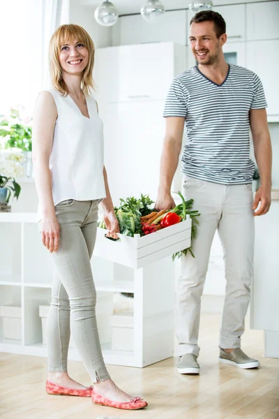 Молодая пара с овощной коробкой на кухне — стоковое фото