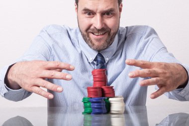 Olgun adam açgözlü bakan cam masada poker fişleri ile