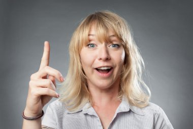 Parmak ile işaret gri arka plan üzerinde genç kadın portre