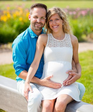 Mutlu çift bekliyor bebek parktaki bankta oturmuş,