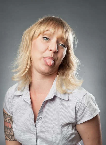 Retrato de mujer joven sobre fondo gris, sobresaliendo de su lengua —  Fotos de Stock