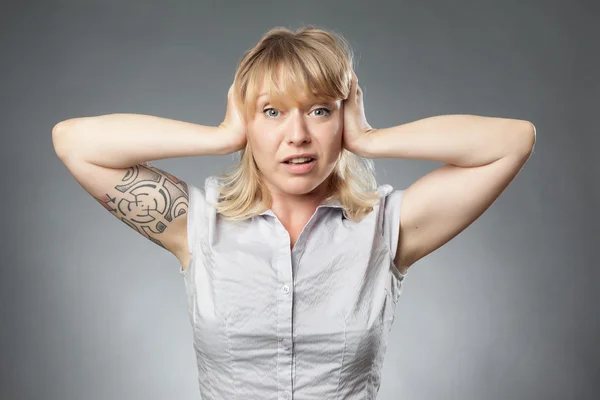 Retrato de mujer joven sobre fondo gris, cubriéndose las orejas — Foto de Stock