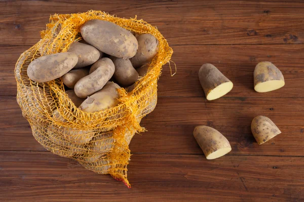 Картофель в сетке на дереве, наполовину — стоковое фото