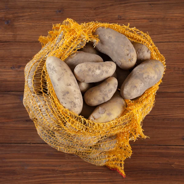 Картофель в сетке на дереве — стоковое фото