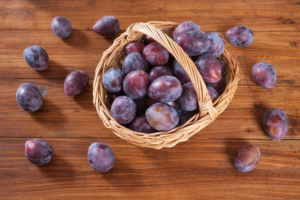 Cesta con ciruelas sobre madera — Foto de Stock