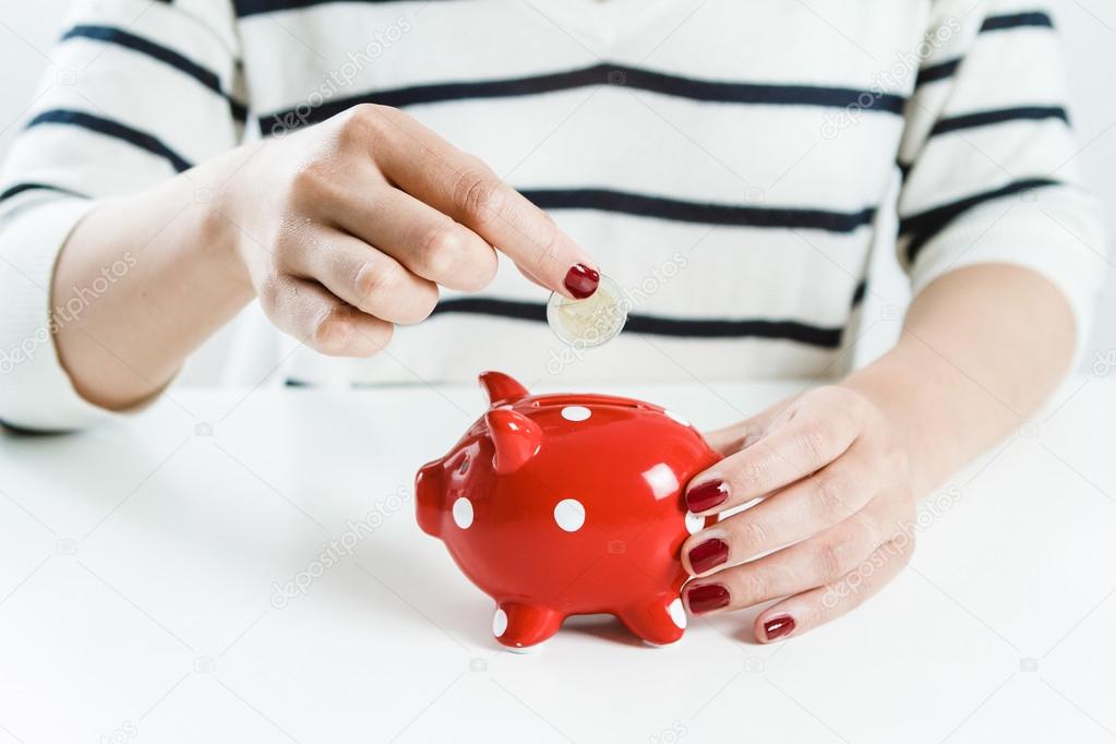 Woman saving money with red piggy bank