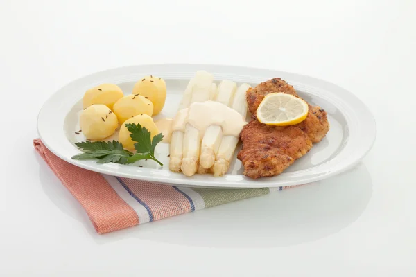 Schnitzel Vienna con salsa su asparagi e patate in piatto — Foto Stock