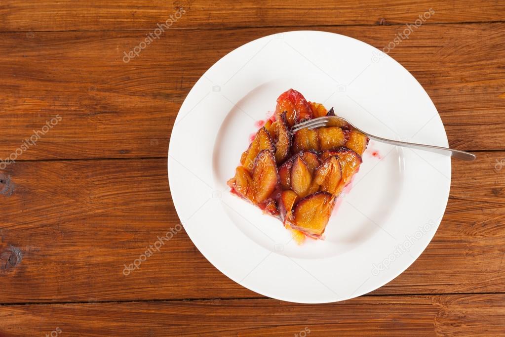 Plate with plum cake, piece of cake and fork