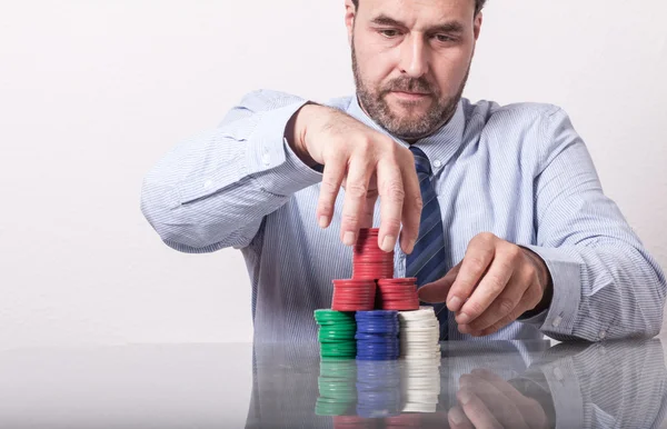 Reifer Mann mit Pokerchips auf Glastisch, sortiert Stapel — Stockfoto