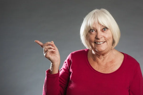 Female senior showing with finger to side. — Stock Photo, Image