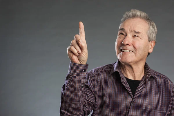 Hombre mayor sonriendo, dedo señala a la parte superior . — Foto de Stock