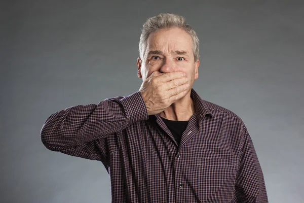 Male senior holding hands over mouth. — Stock Photo, Image