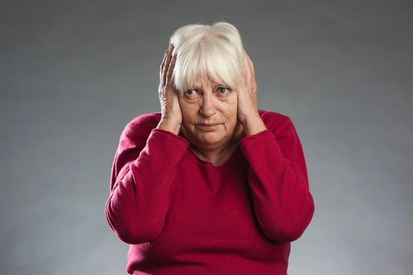 Female senior sticking fingers into ears. — Stock Photo, Image