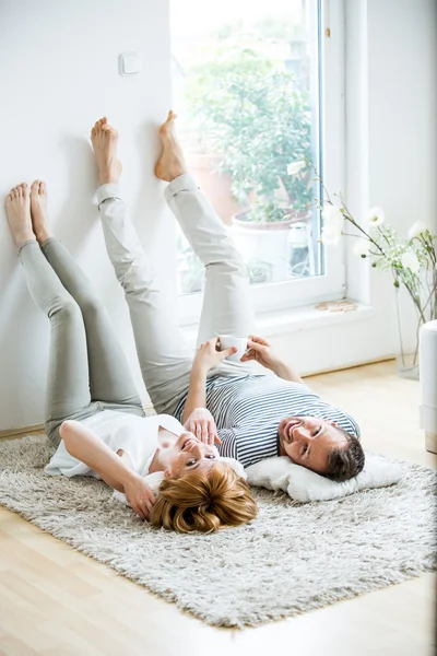 Fiatal pár feküdt a szőnyegen, a nappaliban — Stock Fotó