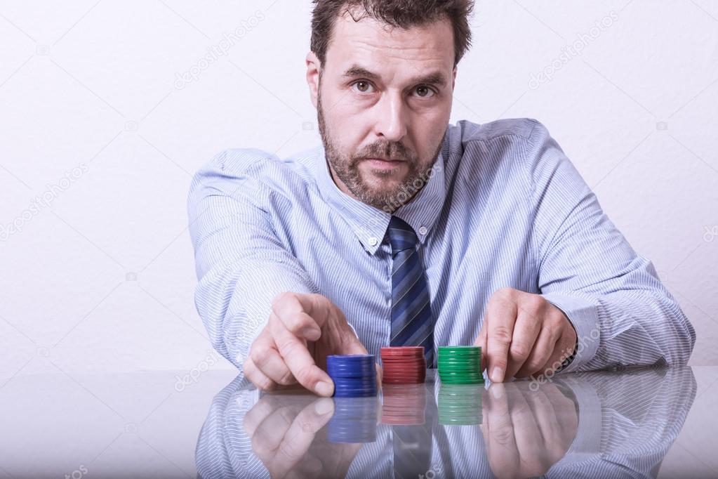 Mature man with poker chips on glass table, sorting stacks