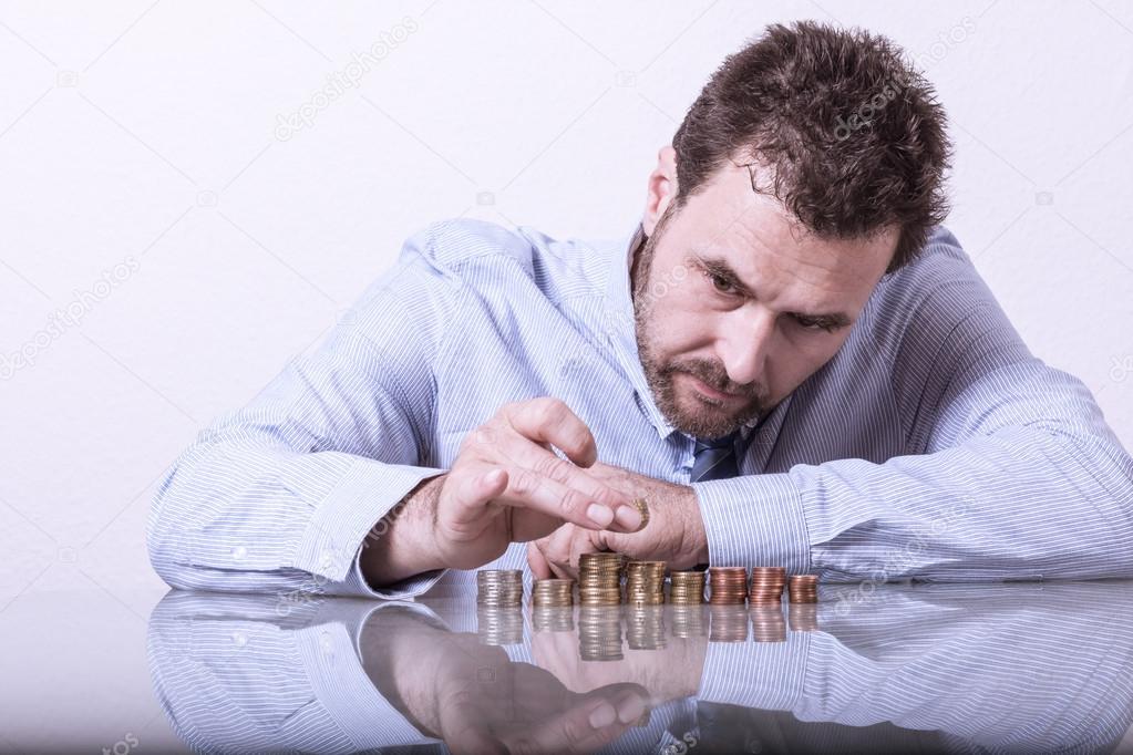Business man counting money, stacks of coins on office desk