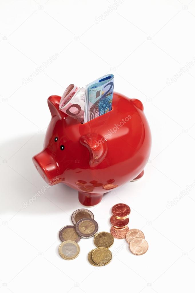 Red piggy bank with euro notes and coins