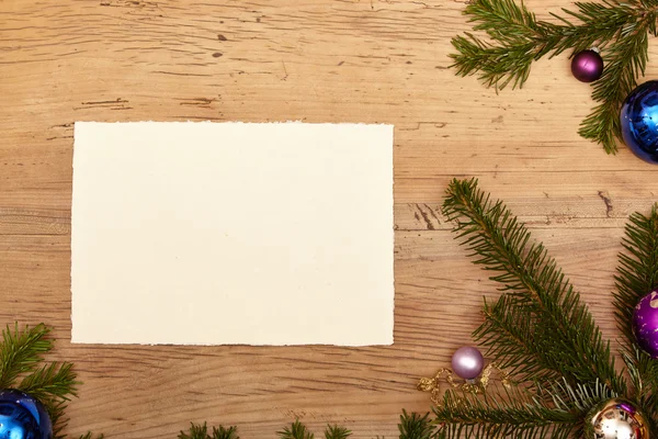 Fir twijgen, kerstballen en lege kaart op hout — Stockfoto