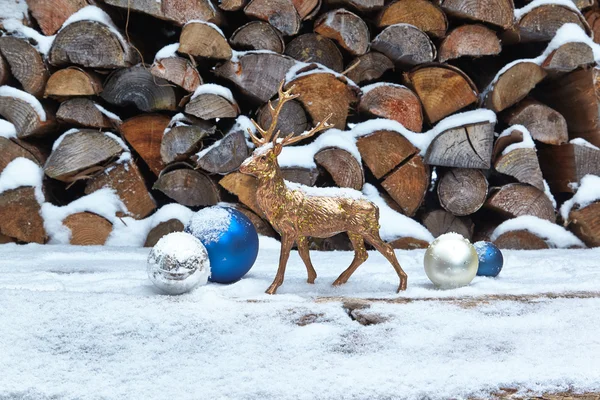 Hirschfigur und Kugeln im Schnee, Holzstapel — Stockfoto