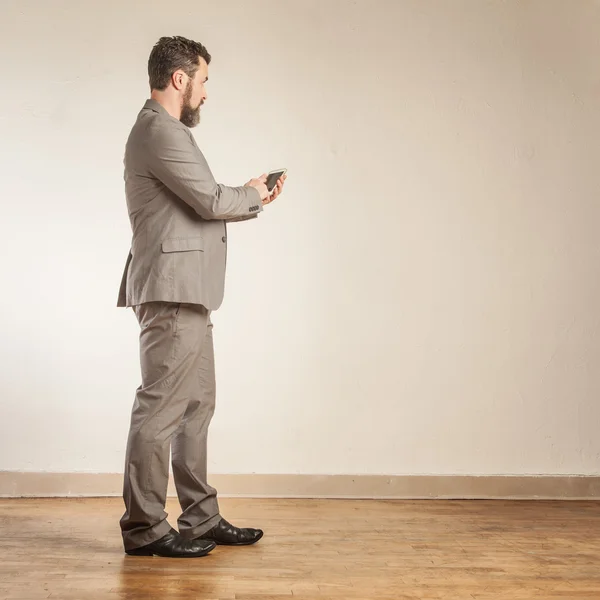 Ώριμη επιχείρηση άνθρωπος κάνει σημειώσεις σχετικά με έξυπνο τηλέφωνο ενώ κοιτάζοντας — Φωτογραφία Αρχείου