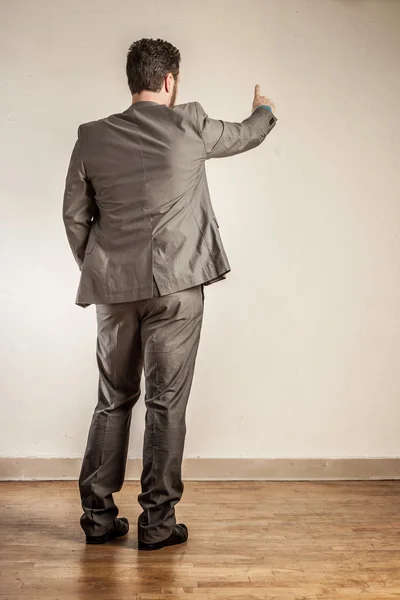 Mature business man from behind, pointing finger at wall — Stock Photo, Image