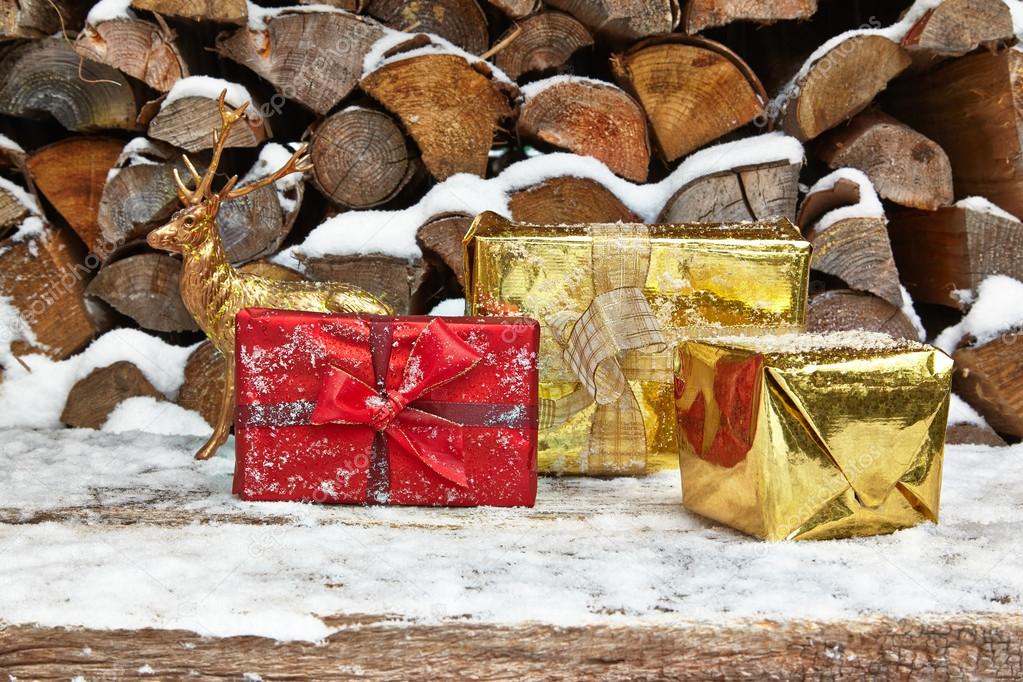 Christmas presents and deer figurine in front of woodpile