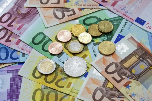 Monedas en euros en un montón de billetes en euros — Foto de Stock