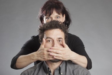 Mature couple woman covering man's mouth clipart