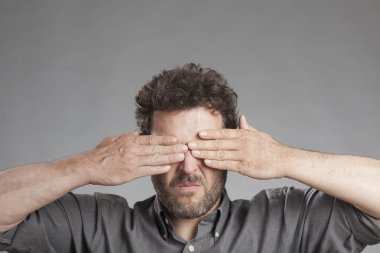 Mature man covering eyes clipart