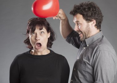 Olgun çift eğleniyor şaka isabet kadının kafasını kırmızı kalp balon şeklinde dostum.