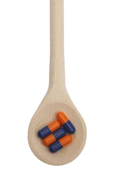 Таблетки на дерев'яній ложці, що символізують хімічне забруднення їжі — стокове фото