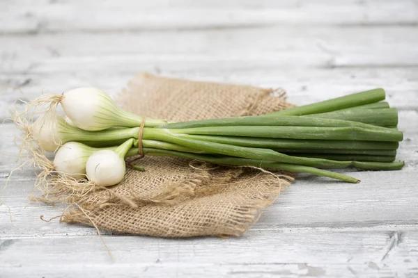 Spring onions on wooden floor — Stock Photo, Image