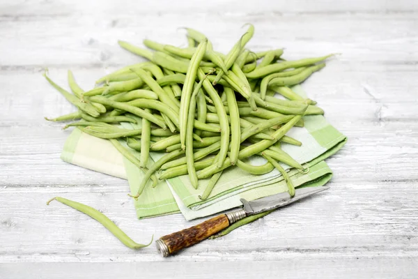 Ωμά πράσινα φασόλια (Phaseolus vulgaris) αντίκες μαχαίρι σε πετσέτα υφασμάτων — Φωτογραφία Αρχείου