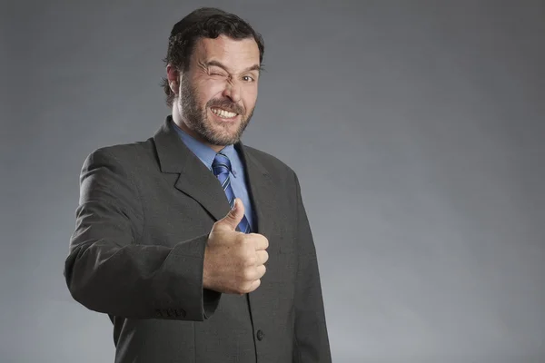 Businessman showing thumbs up against gray background — Stock Photo, Image