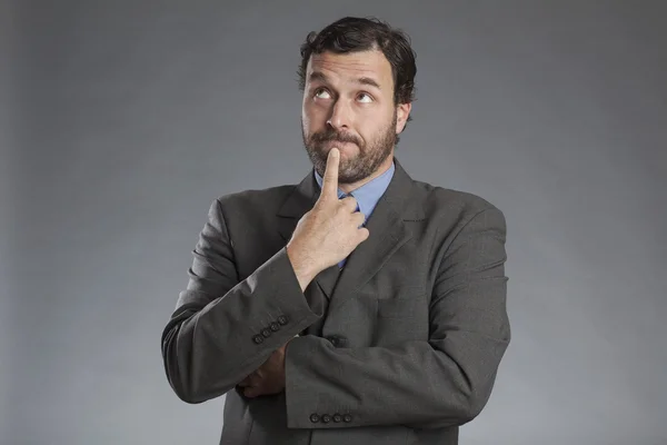 Empresario contemplativo de pie sobre fondo gris — Foto de Stock