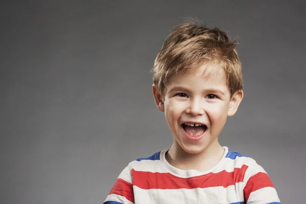 Jonge jongen lachen tegen de grijze achtergrond, portret — Stockfoto