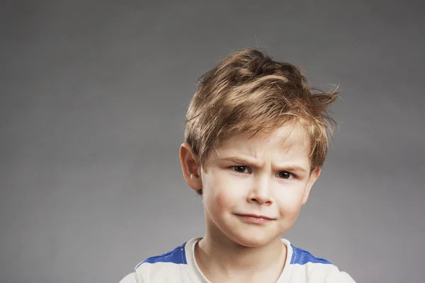 Niño mirando escéptico, cejas fruncidas contra el fondo gris, retrato —  Fotos de Stock