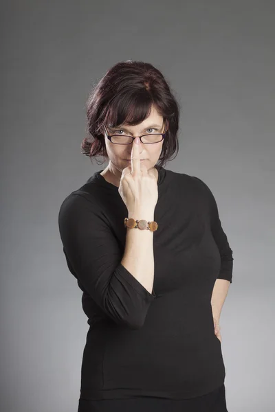 Mature brunette woman wearing glasses against gray background — Stock Photo, Image