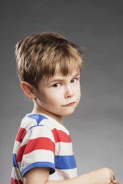 Молодий хлопчик виглядає сумно на сірому фоні, вид збоку — стокове фото