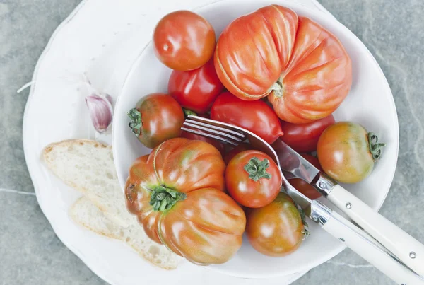 Italy, Tuscany, Magliano, Close up of tomatoes in bowl with bread slice and cutlery — ストック写真