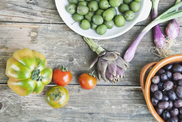 Italia, Toscana, Magliano, Olive in ciotola, cipollotti, pomodori e carciofi su tavola di legno — Foto Stock